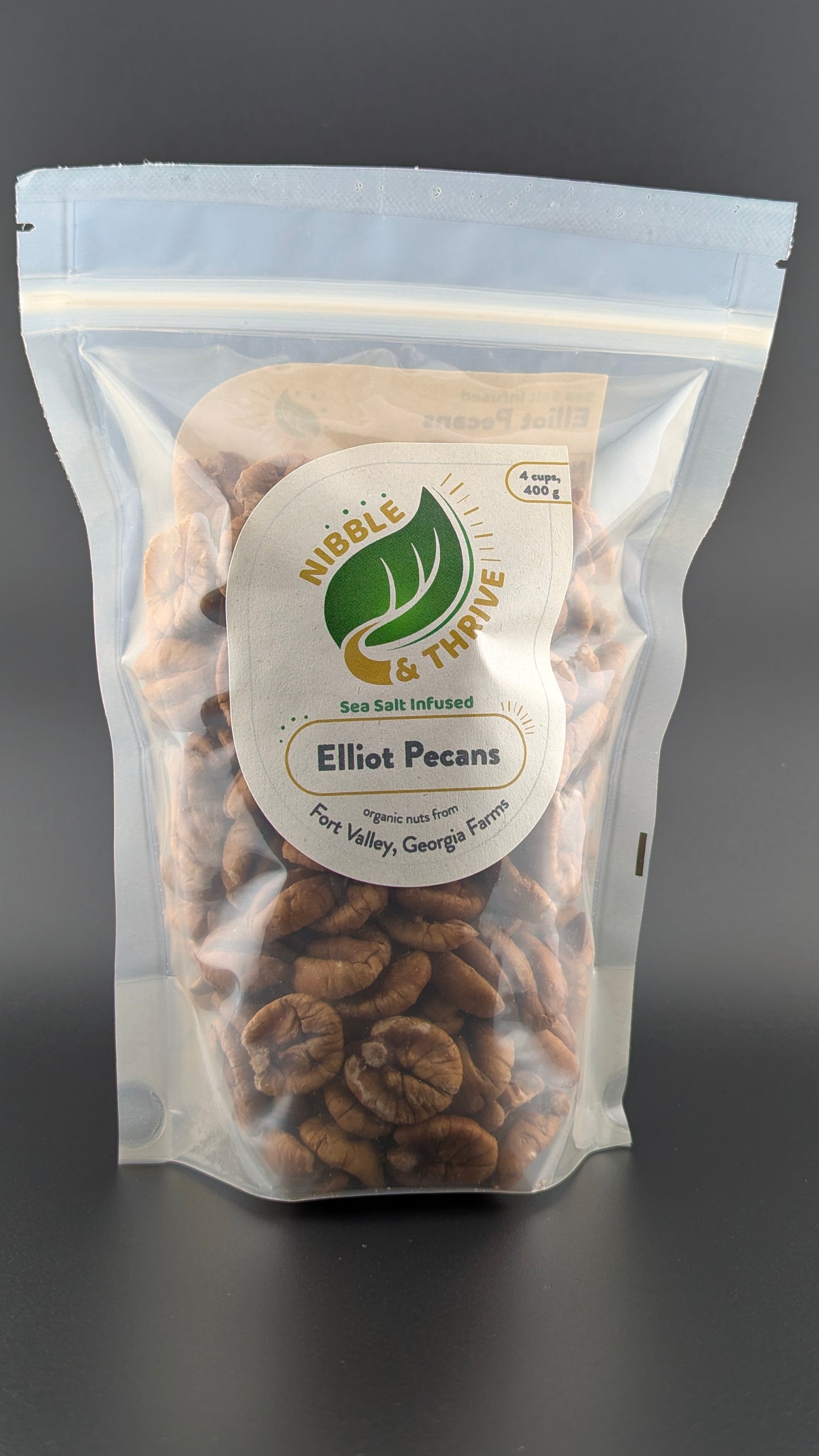 A 4.8 oz resealable bag of Nibble & Thrives organic Infused Elliot Pecans from Fort Valley, GA farms features a visible display of nutritious nuts with a light sea salt infusion.