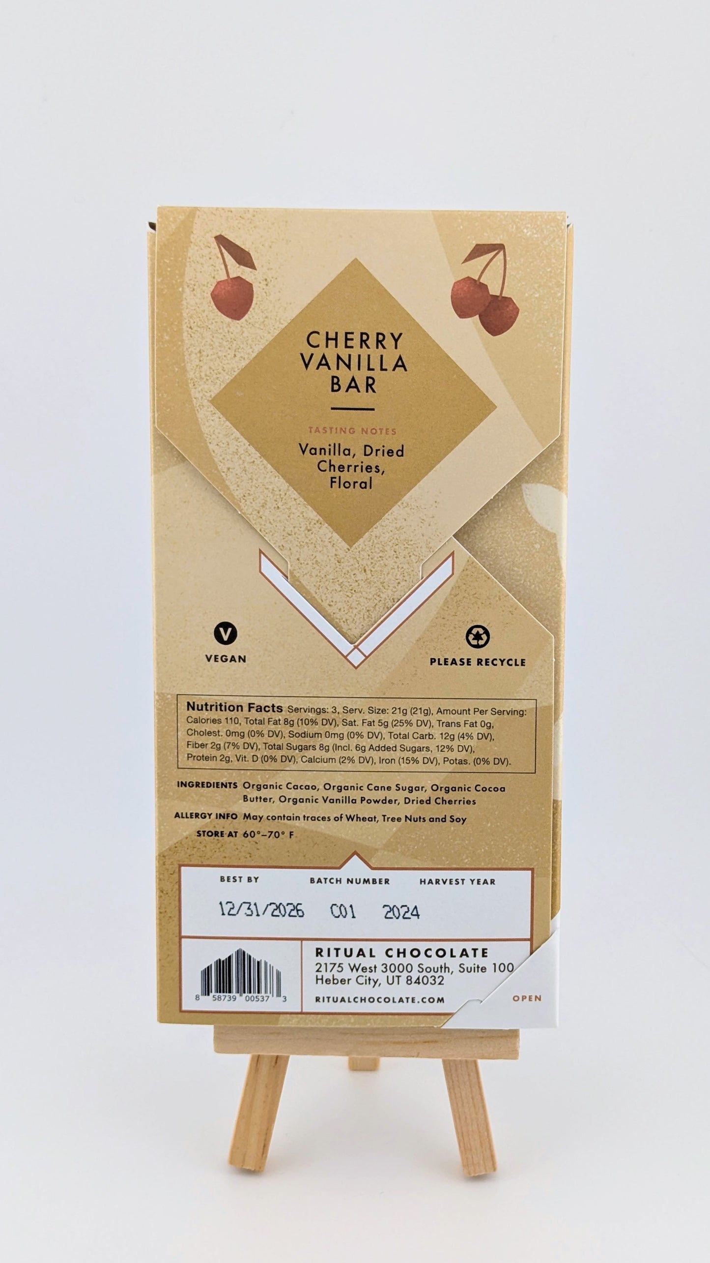 The Ritual Cherry Vanilla Bar 70% 2.12 oz combines Ritual Vanilla Chocolate with Montmorency cherries and floral notes. This vegan bar is presented on an easel and includes recycling symbols, nutrition facts, ingredients, and an expiration date of 12/31/2026.